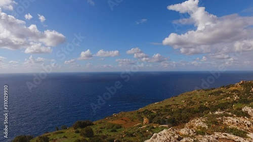 Beautiful Dingli Cliffs landscape. Fluffy white clouds over the Hamrija Tower (Torre Della Pietra Nigra) Panement left reveals calm mediterranean sea on a sunny day photo