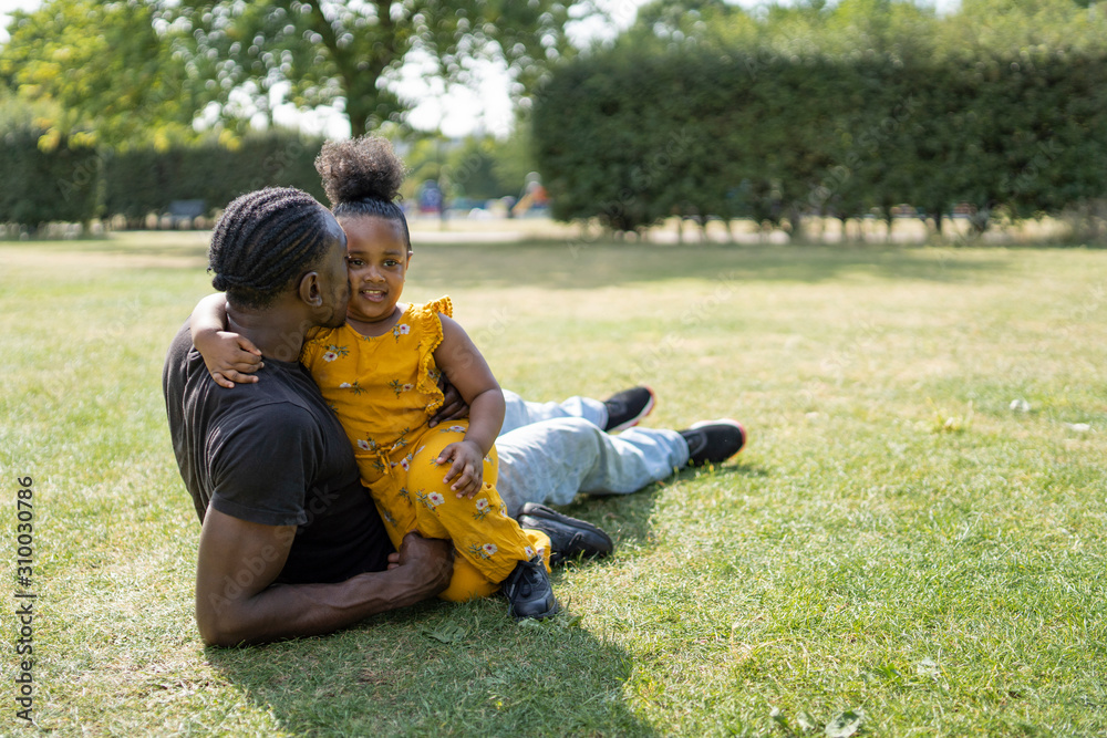 Affectionate father and daughter relaxing on a meadow in a park Affectionate father and daughter relaxing on a meadow in a park
