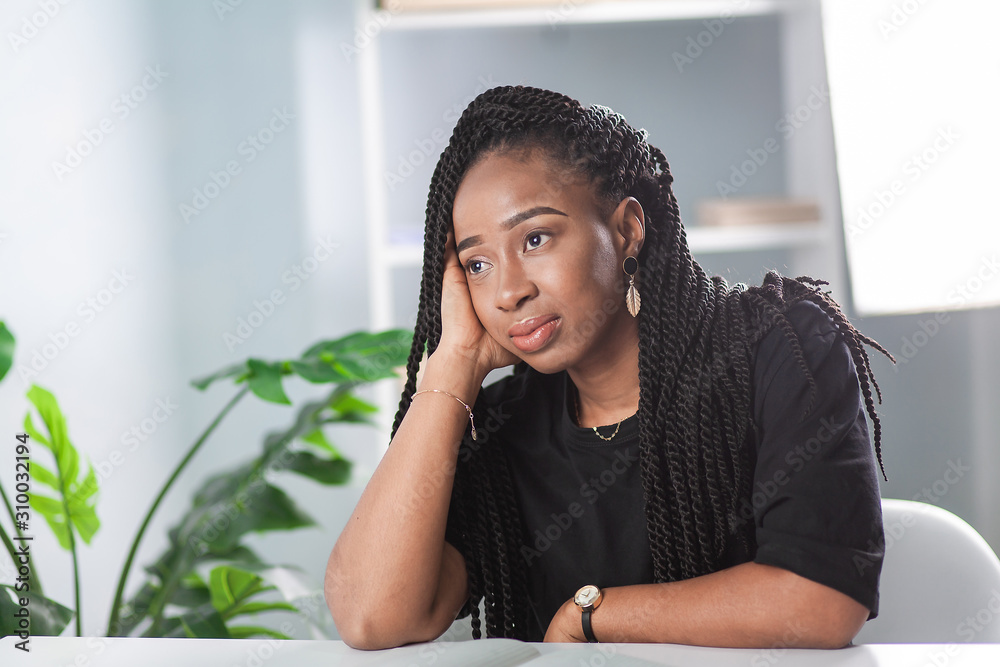 African American girl sitting in the office at the table. Business ...