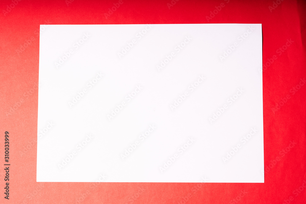 A white sheet of A4 paper on a red background. The view from the top A white sheet of A4 paper on a red background. The view from the top