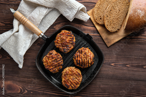 Fototapeta Naklejka Na Ścianę i Meble -  Top view of cast iron grill pan with beef cutlets and freshly baked brown bread