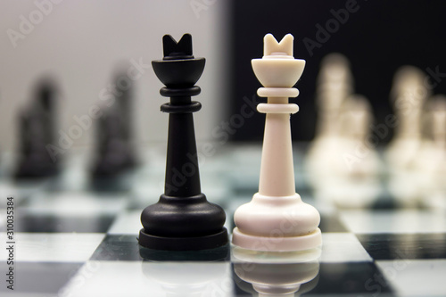white and black king stand on a chessboard on the background of blurry remaining pieces on a black and white background