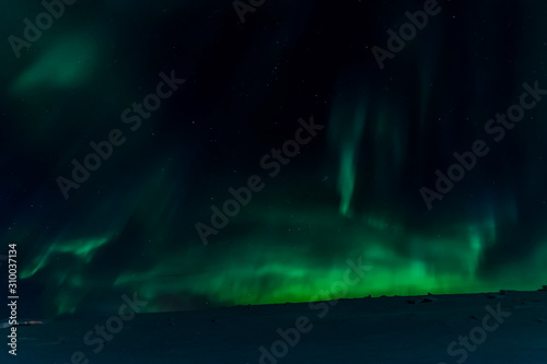 Aurora borealis in night northern sky. Ionization of air particles in the upper atmosphere.