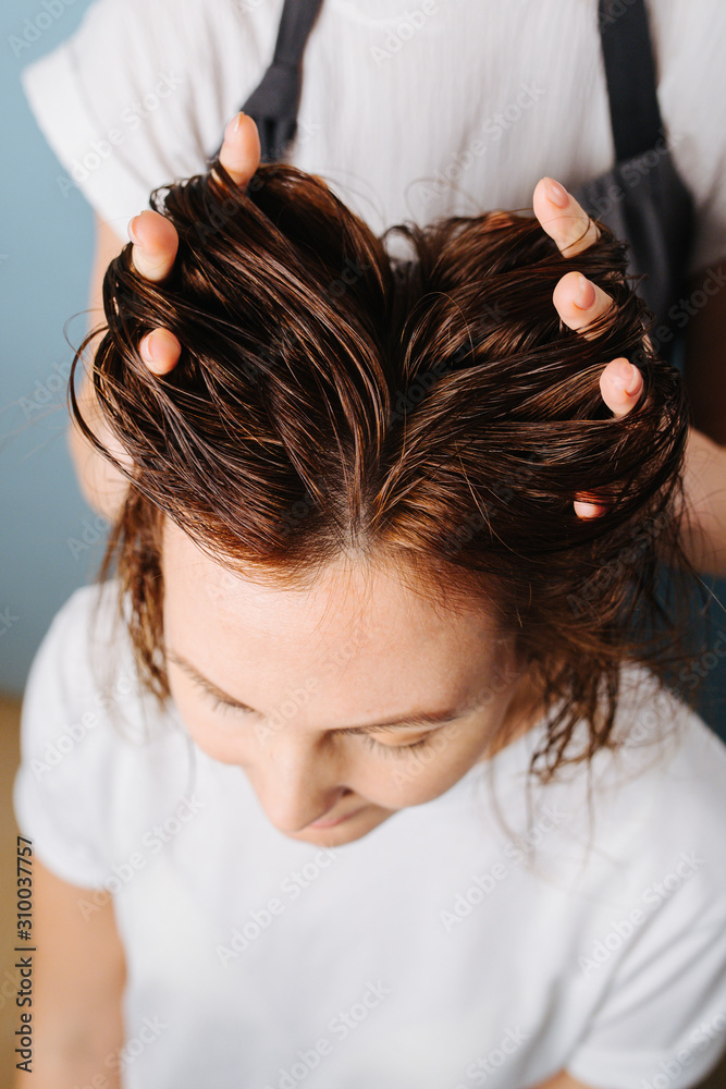 Naklejka premium Hairdresser running fingers through client's hair to prepare it for trimming.