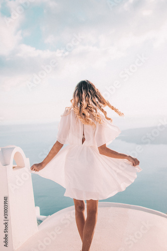 Fototapeta Naklejka Na Ścianę i Meble -  Young woman with blonde hair on rooftop in santorini greece