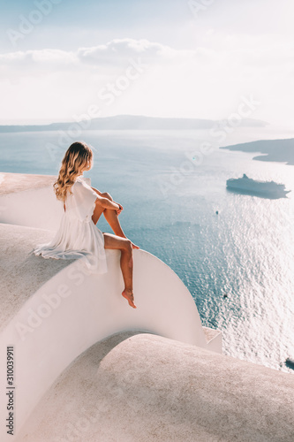 Fototapeta Naklejka Na Ścianę i Meble -  Young woman with white dress on rooftop in santorini greece