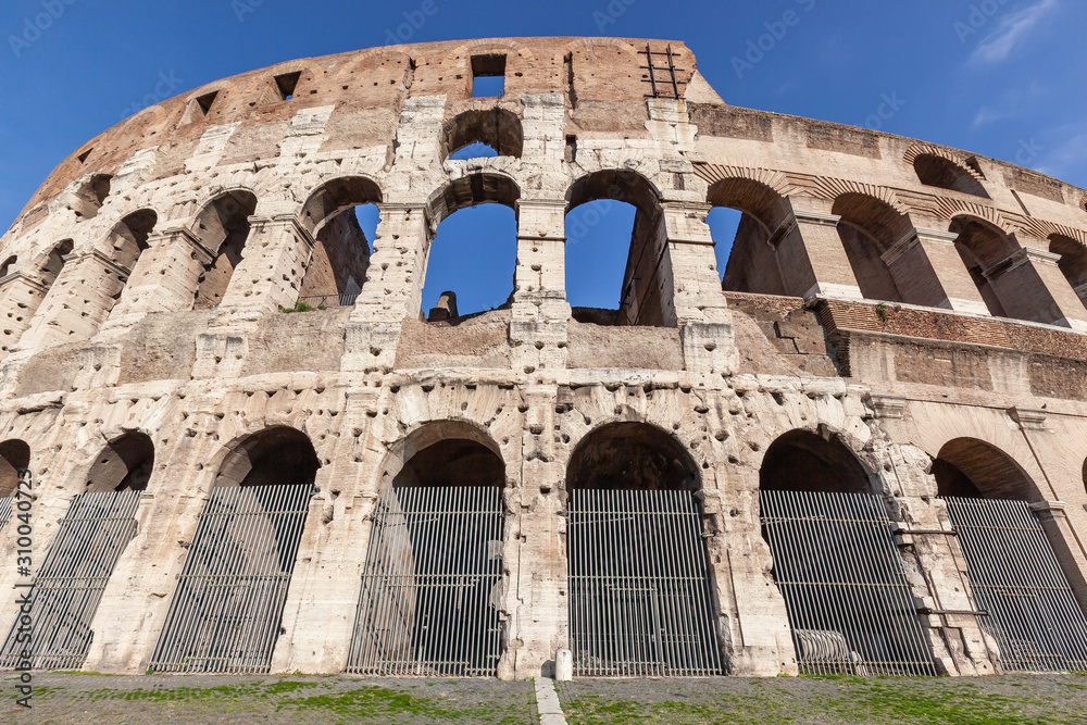 Part of the wall of the ancient Roman Colosseum against blue sky, Italy