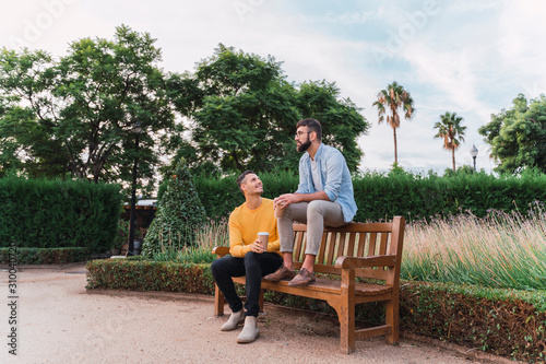 Wallpaper Mural Gay couple relaxing with coffee to go on wooden bench in a park, Barcelona, Spain Torontodigital.ca