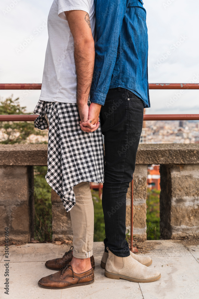 Crop view of gay couple standing back to back holding hands, Barcelona, Spain Crop view of gay couple standing back to back holding hands, Barcelona, Spain