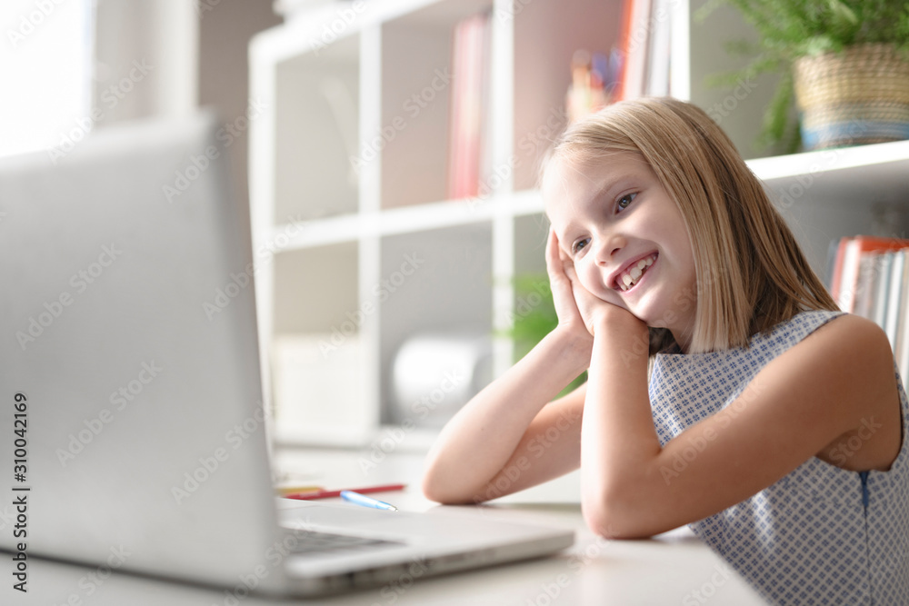 Happy girl sitting at table at home using laptop Happy girl sitting at table at home using laptop