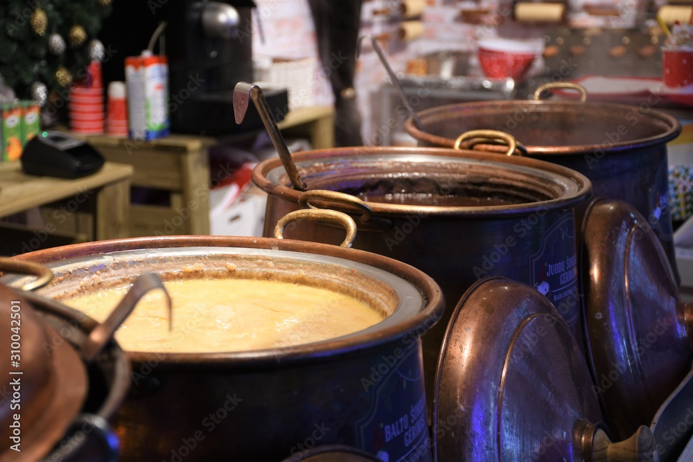 Large copper pot for hot white and dark chocolate in a Christmas market, ready to eat, street food in winter