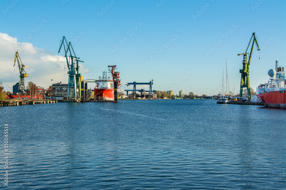 View of the shipyard with historical cranes in the industrial part of the city Gdansk (Gdańsk) in Poland (Polska). The shipyard is close to the old town. Peaceful Motlawa river.