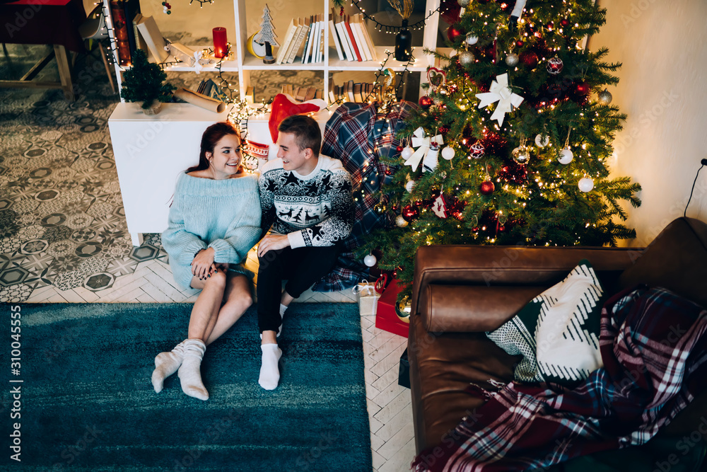 Laughing young couple relaxing at decorated house on Christmas