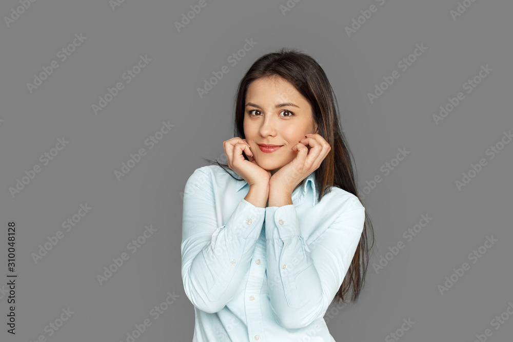 Freestyle. Young woman standing isolated on grey holding face smiling cute Freestyle. Young woman standing isolated on grey holding face smiling cute