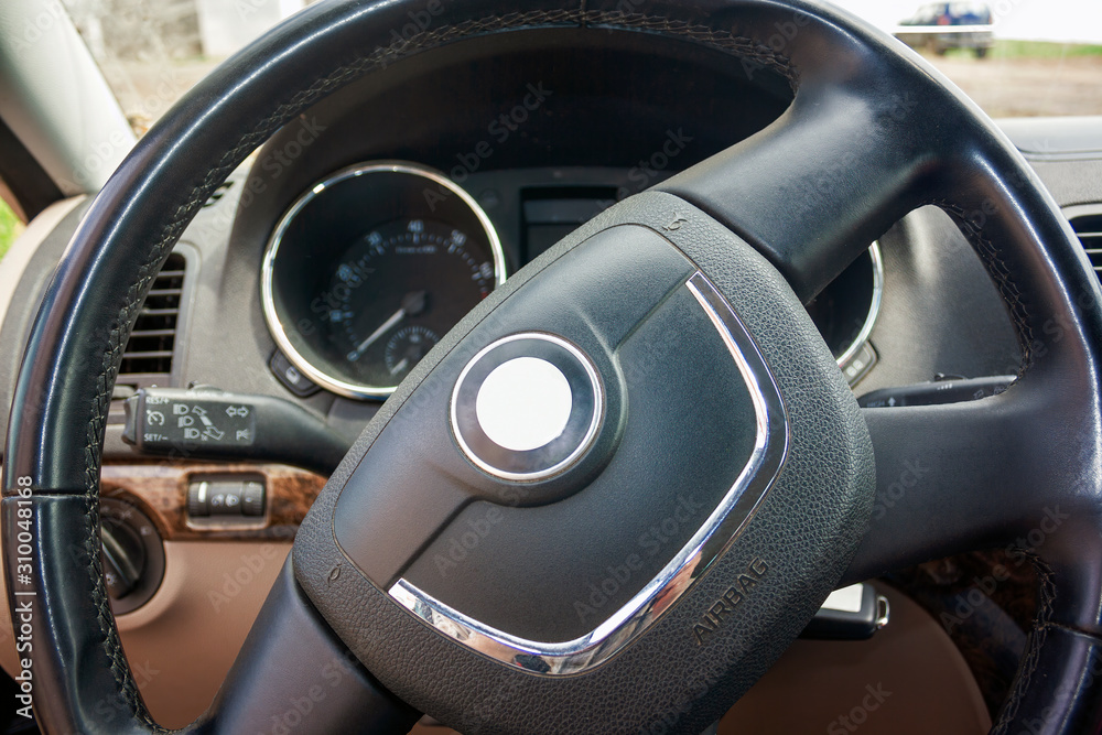 Steering wheel of a passenger car close-up. View of the interior of a modern automobile showing the dashboard.