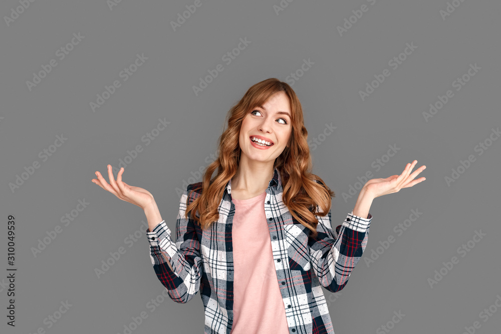 Copy Space for Text or Product . Stylish woman studio standing isolated on grey hands aside looking up dreamful Copy Space for Text or Product . Stylish woman studio standing isolated on grey hands aside looking up dreamful