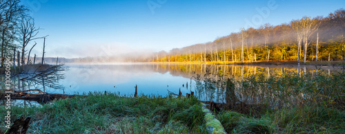 Herbst im Müritz Nationalpark, stiller kleiner See mit Morgennebel umgeben von buntem Wald