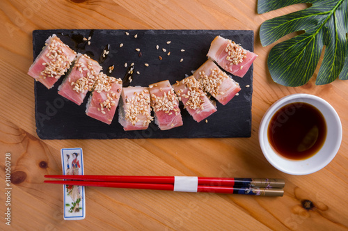 sushi roll with bacon, red chopsticks, soy sauce, top view, sushi menu. Japanese food, on wood background.