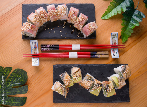 sushi roll with bacon, grilled eel, avokado red chopsticks, soy sauce, top view, sushi menu. Japanese food, on wood background.