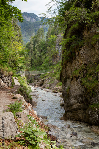 Austria, Tyrol, Erpfendorf, Stream flowing under suspension bridge in Griesbach Gorge photo