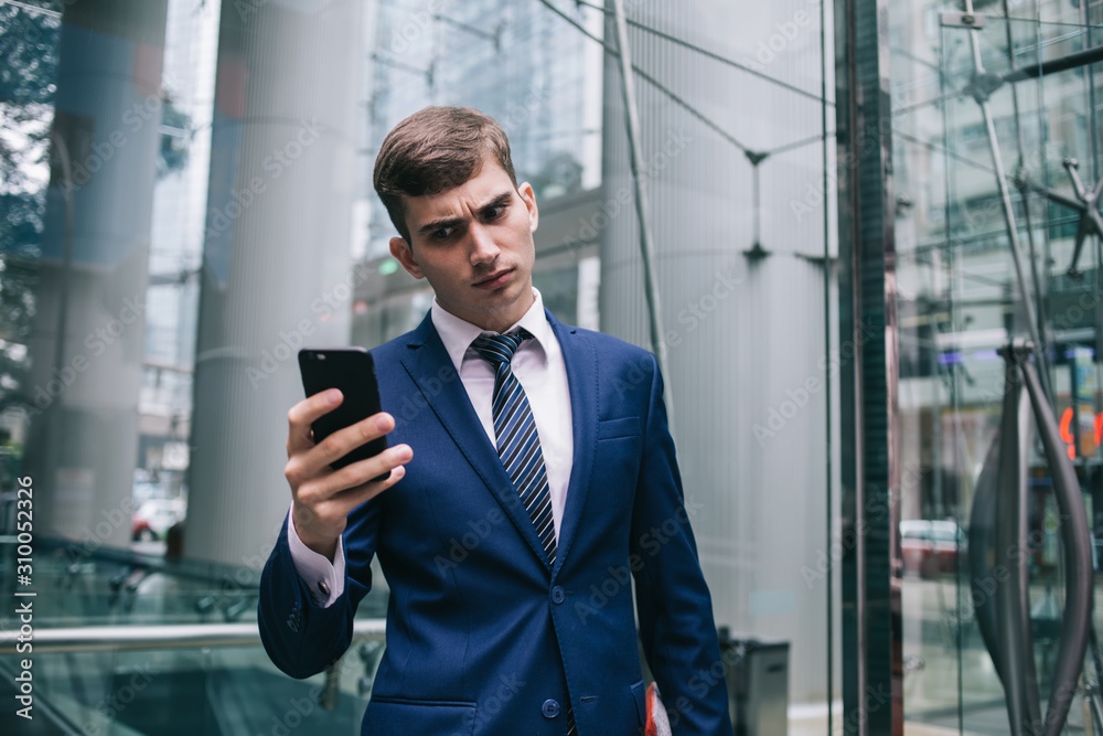 Businessman frowning looking at smartphone screen
