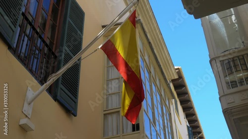 Spanish Flag Waving on Flag Pole Attached to Building Under Window photo
