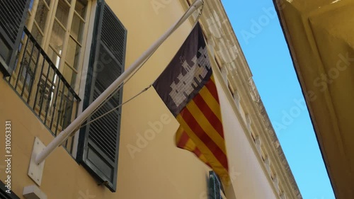 Catalonian Flag Waving on Flag Pole Attached to Building Under Window photo