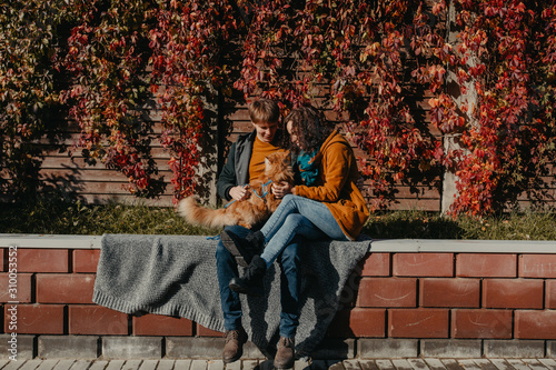 Young couple with a red cat on a background of an autumn city.
