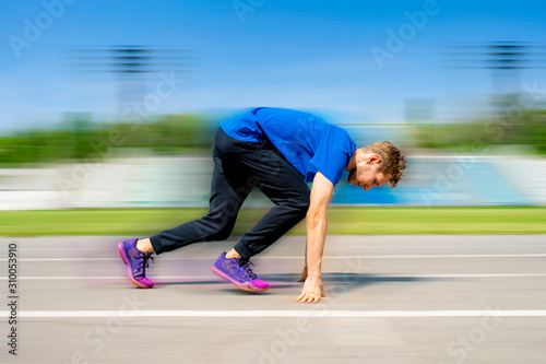 young runner athlete in the low start position on the sports track on stadium outdoor