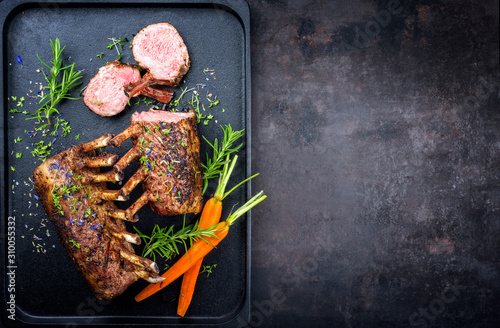 Foto Barbecue rack of lamb with carrot and herbs offered as top view on a modern desi