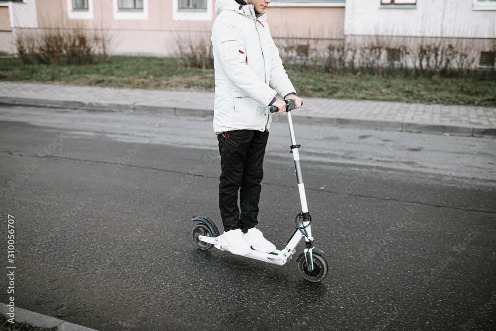 man rides a white electric scooter on a frosty winter day. Electric transport. man rides a white electric scooter on a frosty winter day. Electric transport.