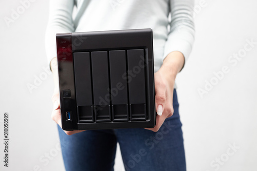 girl person hold in hands portable office or home data nas server. device for backup important information. copy space. four hdd slots and usb version 3 plug photo