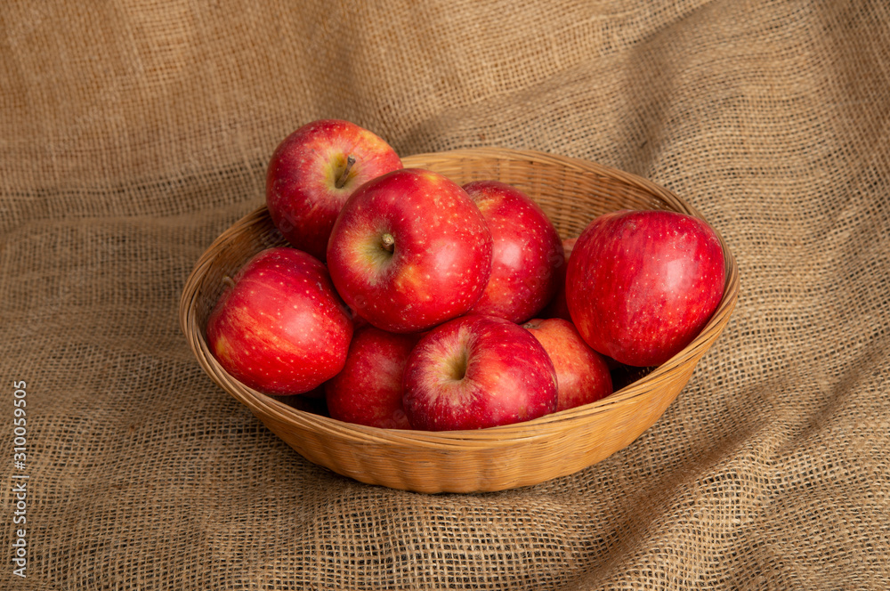 Fresh red apples in basket on sack background with copy space Fresh red apples in basket on sack background with copy space