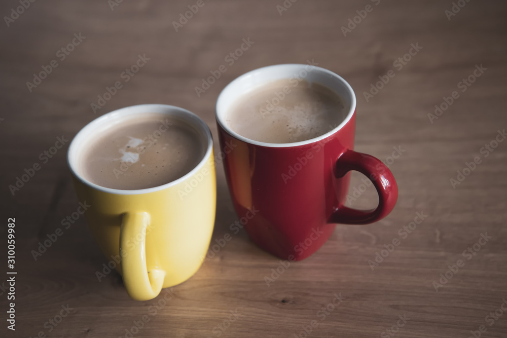 Two cups of cappuccino with latte art on wooden background. Beautiful foam, greenery ceramic cups, stylish toning, place for text. Two cups of cappuccino with latte art on wooden background. Beautiful foam, greenery ceramic cups, stylish toning, place for text.