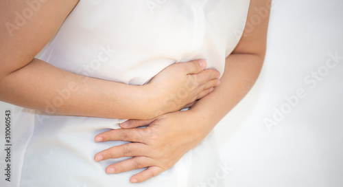 The image of an Asian woman holding her hand in her stomach because of a stomachache, because of a stomachache and having food-borne infections in a white background. © Bussarin