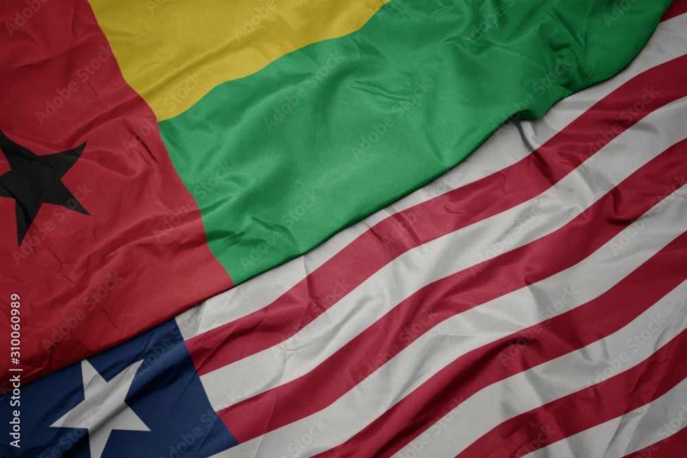 waving colorful flag of liberia and national flag of guinea bissau.