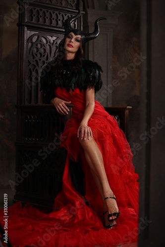 Model in the image of a witch in a red dress.