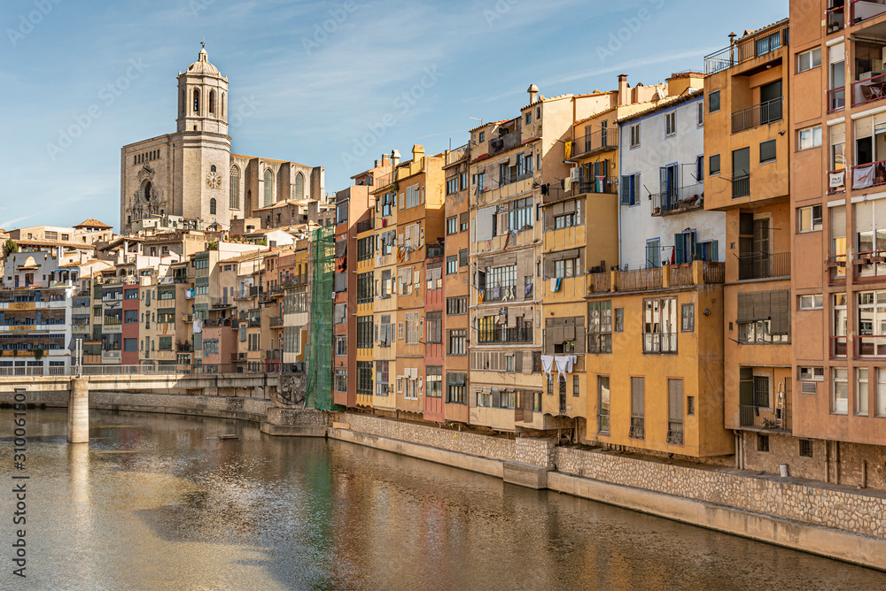 Girona’s Cathedral above the Onyar River. Colorful red, orange and yellow houses and bridge besides the Onyar river in Girona, Catalonia, Spain