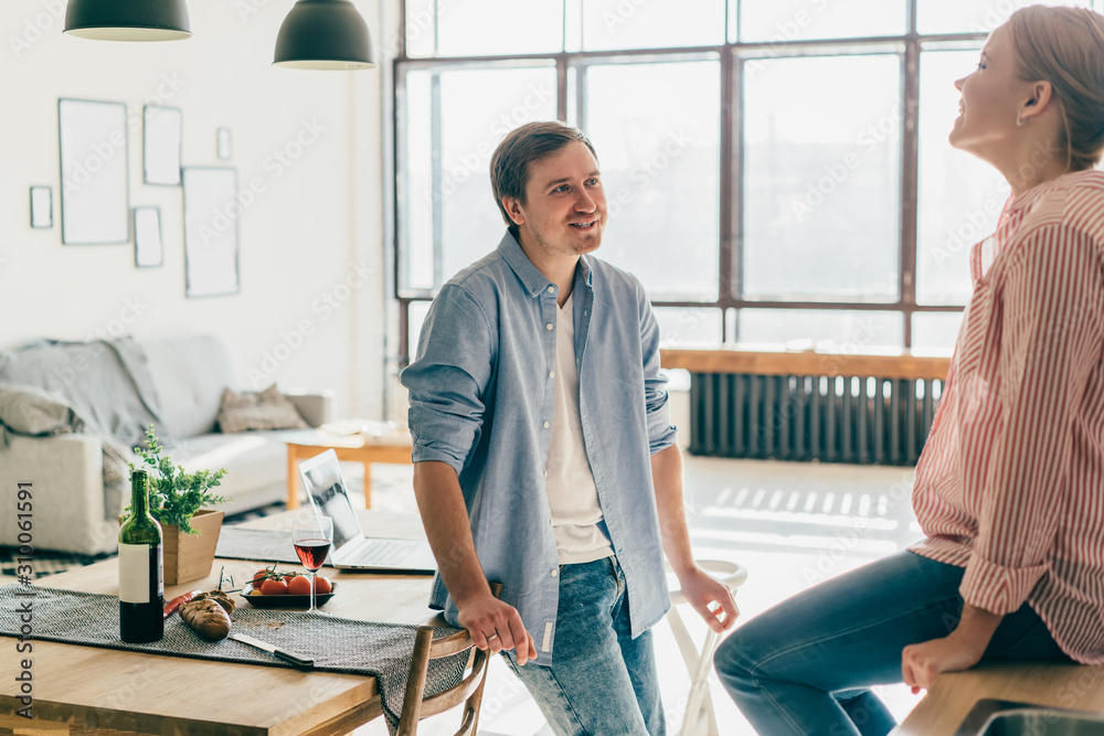 Obraz premium Smiling young couple in kitchen looking at each other