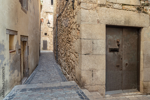 Fototapeta Naklejka Na Ścianę i Meble -  Narrow medieval street in Girona. Girona's typical narrow street in a medieval village in Northern Catalonia