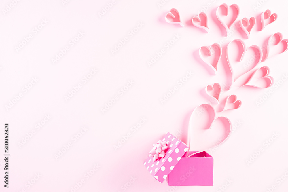 Pink paper hearts splash out from gift box on Light pink pastel paper background. Love and Valentine's day concept.