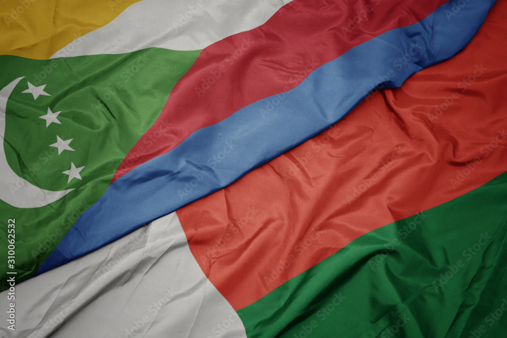 waving colorful flag of madagascar and national flag of comoros.