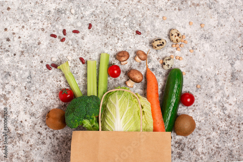 paper shopping bag with green health food on the gray backgraund. vegan and vegetarian concept. close up, copy space