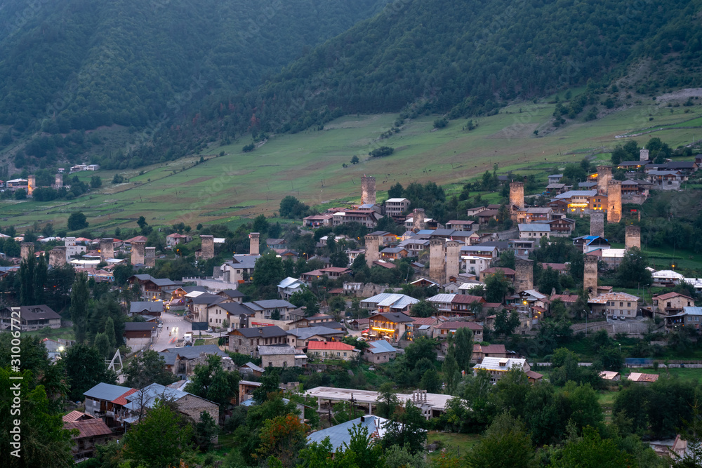 Evening view on Mestia with its beautiful illuminated Svan Towers and high mountains. Svaneti, Georgia.