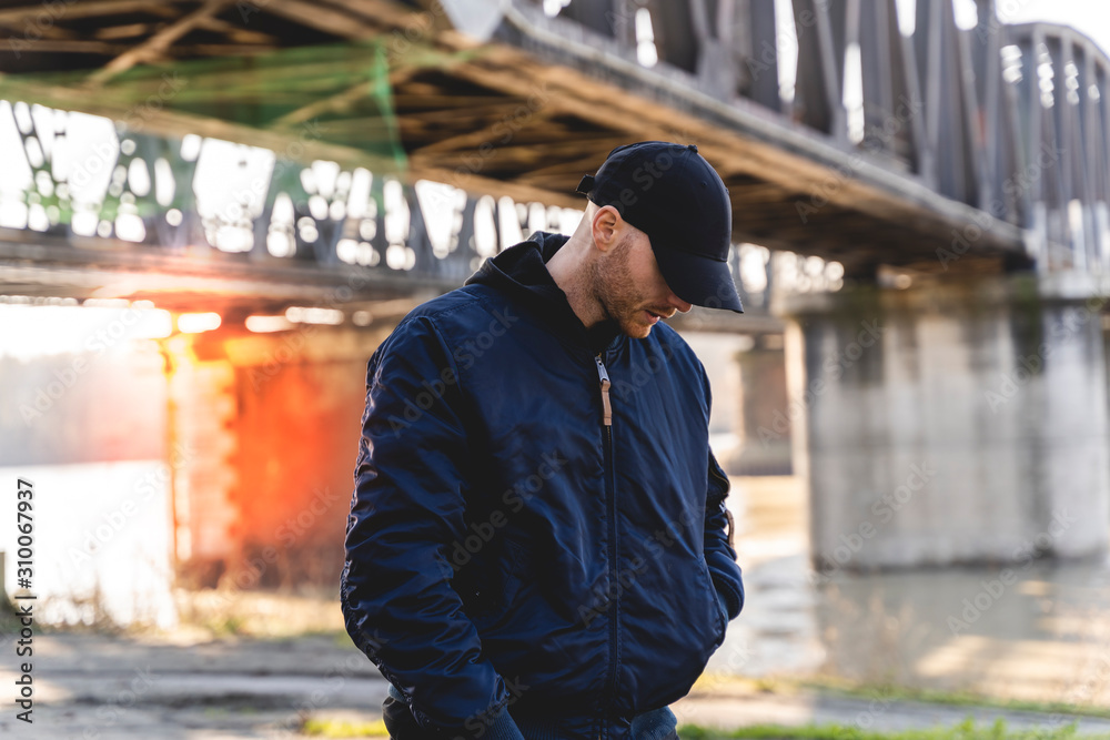 portrait of young rapper posing under a metal bridge portrait of young rapper posing under a metal bridge