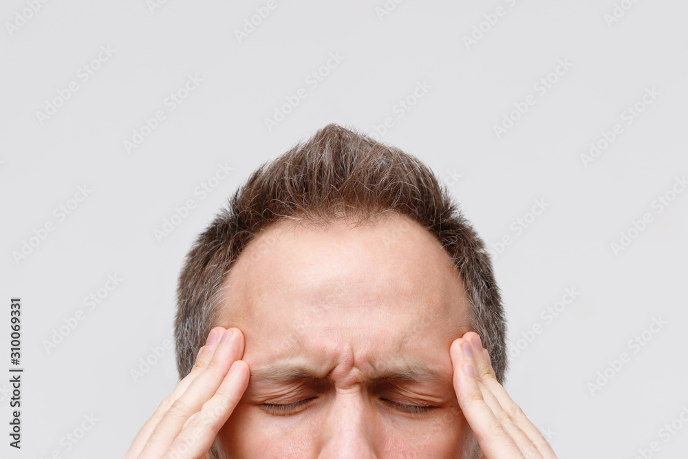 Headache, nervous tension, temporal and throbbing pain concept. Close up portrait of man massaging his temples, closed eye, isolated on gray background. Strong migraine Headache, nervous tension, temporal and throbbing pain concept. Close up portrait of man massaging his temples, closed eye, isolated on gray background. Strong migraine