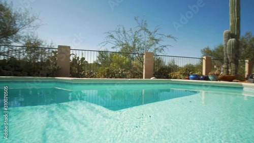 Panning over a backyard swimming pool. The private residential pool is perfect for a refreshing swim during hot summer months. Panning shot can promote vacation home rentals and luxury real estate. 