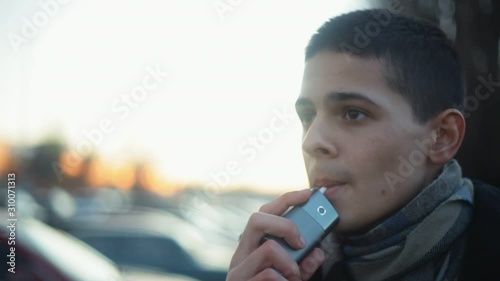 Young boy vaping with help of device for heating tobacco. Alternative of smoking cigarettes photo