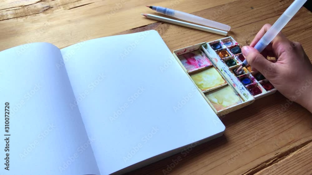 Young Woman artist draw with watercolor paints with a brush in a bullet