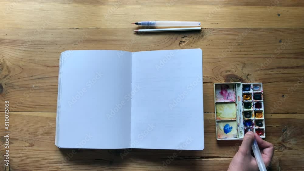 Young Woman artist draw with watercolor paints with a brush in a bullet